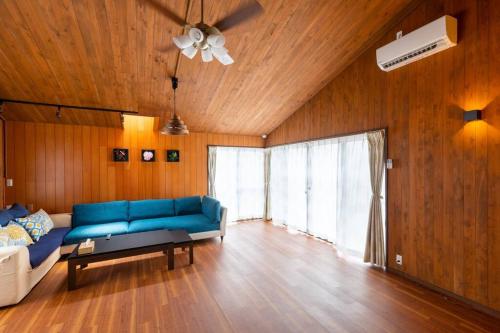 a living room with a blue couch and wooden walls at オーシャニア一宮 in Ichinomiya