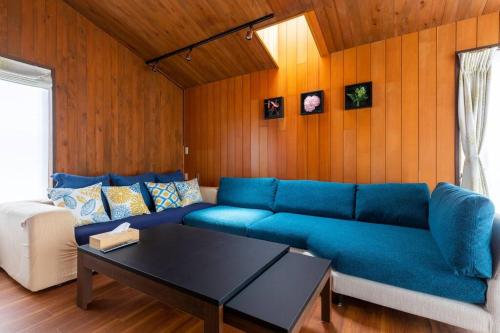 a living room with a blue couch and a table at オーシャニア一宮 in Ichinomiya