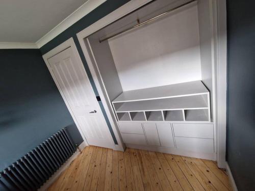 an empty room with a white door and a wooden floor at Beach front apartment in Edinburgh