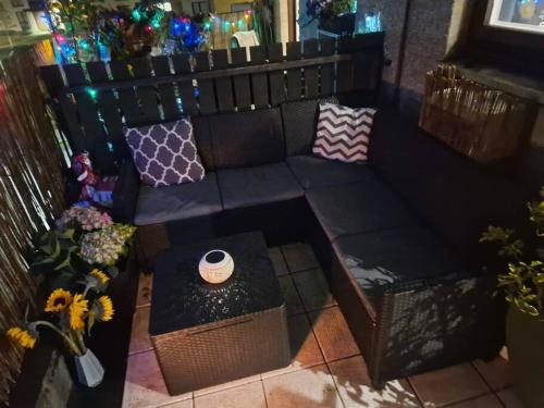 a black couch with pillows on a balcony with flowers at Beach front apartment in Edinburgh