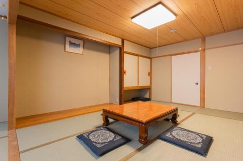 a room with a wooden table and two mats at Shiga Kogen Olympic Hotel in Yamanouchi