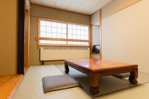 a living room with a table and a window at Shiga Kogen Olympic Hotel in Yamanouchi