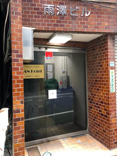 wejście do ceglanego budynku ze szklanymi drzwiami w obiekcie AN HOTEL w Tokio