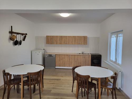 een keuken met 2 tafels en stoelen in een kamer bij Casa Berbece in Moieciu de Jos