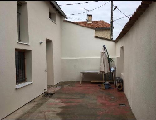an empty courtyard of a white building with a bench at Location meublée à caractère atypique in Puygouzon-et-Montsalvy