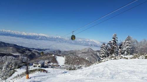 a ski lift with people on a snow covered mountain at Shiga Kogen Olympic Hotel in Yamanouchi