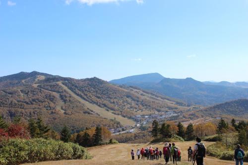 a group of people walking on a hill with mountains in the background at Shiga Kogen Olympic Hotel in Yamanouchi