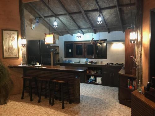 a kitchen with a bar with stools in it at Mae Chan Treehouse with swimming pool in Mae Chan