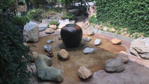 a large vase sitting in a pond of rocks at Mae Chan Treehouse with swimming pool in Mae Chan