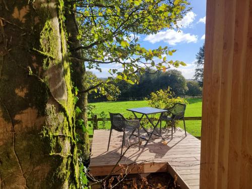 een tafel en stoelen op een houten terras bij Le Refuge de la Doucette in Paimpont