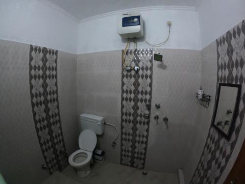 a small bathroom with a toilet and a shower at Hobbit House Hostel in Rishīkesh