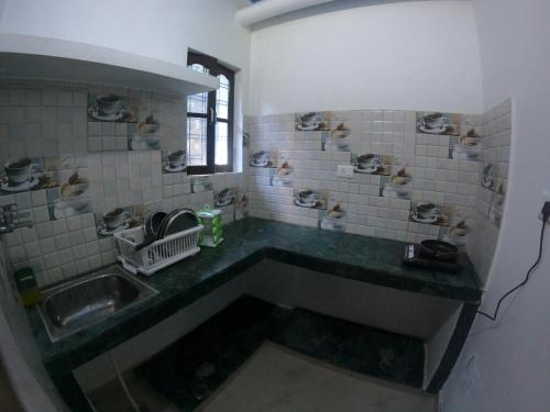 a dirty bathroom with a sink and a window at Hobbit House Hostel in Rishīkesh