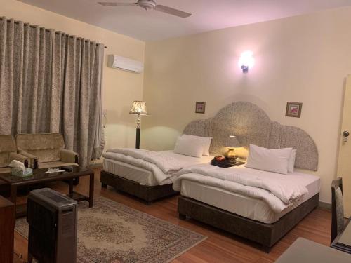 a hotel room with two beds and a living room at The Exclusive House in Peshawar