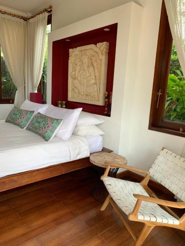 a bedroom with a bed and a chair and a window at Villa Padi in Canggu