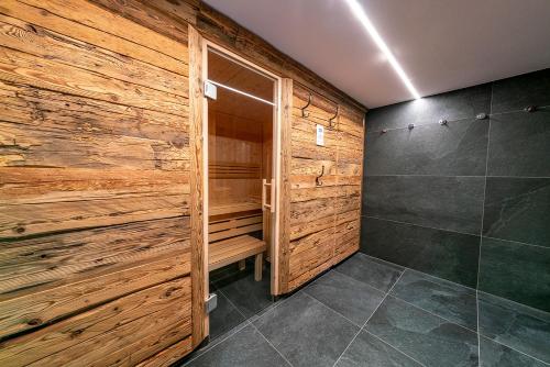 a bathroom with a walk in shower and a wooden wall at Sonnentalhof in Itter