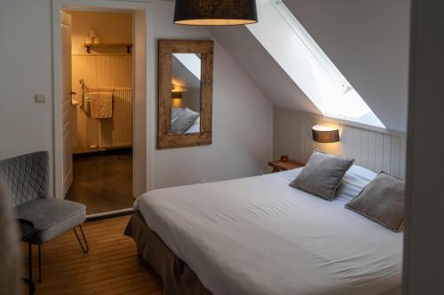 1 dormitorio con cama blanca y espejo en Hotel De Maretak en Dilsen-Stokkem
