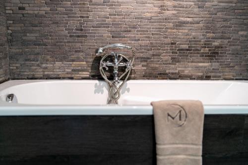 bañera con grifo junto a una pared de ladrillo en Hotel De Maretak en Dilsen-Stokkem
