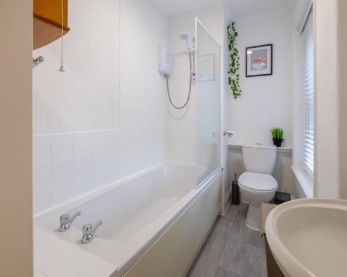 a white bathroom with a tub and a toilet at Stay in the heart of Isle of Wight in 2BDR apt in Newport