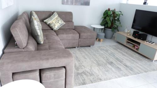 a living room with a brown couch and a flat screen tv at Settle inn Self Catering Units in Colchester