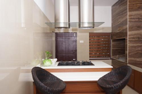 uma cozinha com um fogão e 2 cadeiras em Mother's Inn Homestay em Cochin