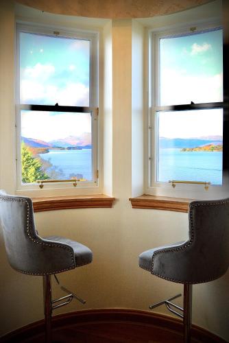 two chairs sitting in a room with two windows at Lomond Castle Penthouse in Luss