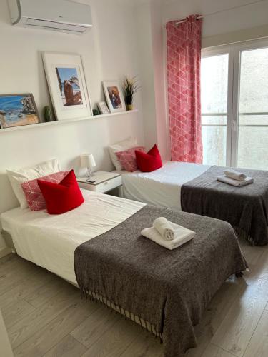 a bedroom with two beds with red pillows and a window at Casa de Oksana in Lagos