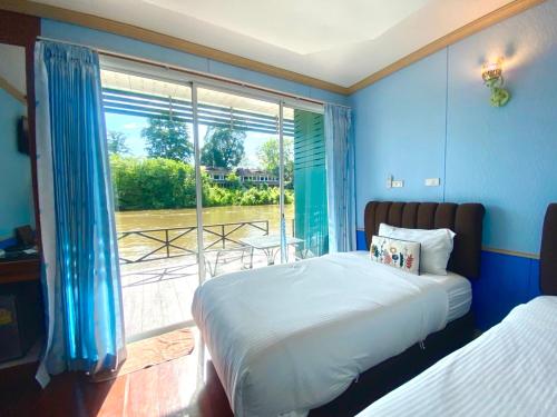 a bedroom with a bed and a large window at Suan Sai Yok Resort in Sai Yok
