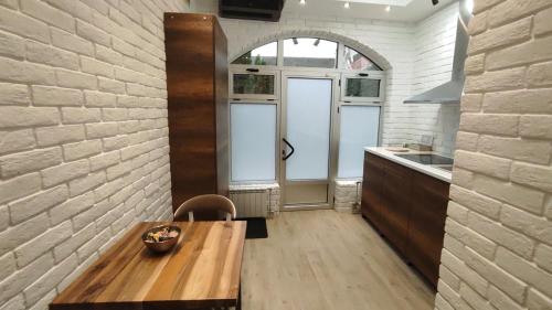 a kitchen with a wooden table and a brick wall at Sky is the limit * Novi Sad * in Novi Sad