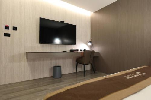 a room with a television on a wall with a chair at Hualien Pink Corner Hotel in Hualien City