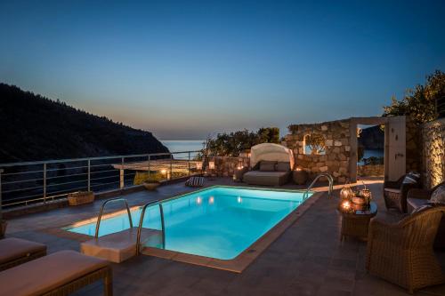 a swimming pool with a view of the ocean at night at Braunis Horio Villas in Asos