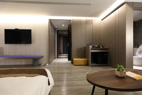 a bedroom with a bed and a table and a tv at Hualien Pink Corner Hotel in Hualien City
