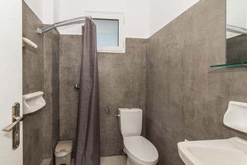 baño con aseo y lavabo y ventana en Odysseas Studios, en Lithakia
