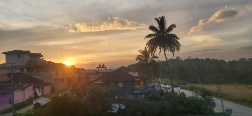 a city with a palm tree and the sunset at M Cube Service Apartments in Sakleshpur