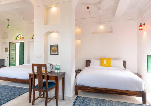 a bedroom with two beds and a table and a desk at Bloom Boutique - Chelon Haveli in Jaipur