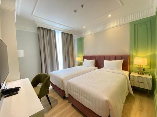 a hotel room with two beds and a desk at Maia Hotel Jakarta in Jakarta