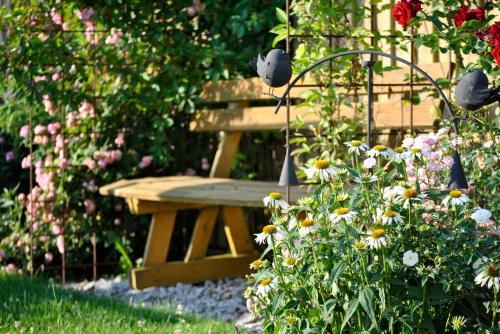 a wooden bench sitting in a garden with flowers at Ferienwohnung Kappauf / Petrik in Friedenfels