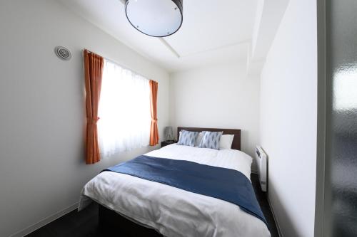 a small bedroom with a bed and a window at GLASS Yamahana EAST in Minami-jūichijō
