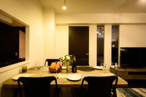 a dining room table with wine bottles and flowers on it at GLASS Yamahana EAST in Minami-jūichijō