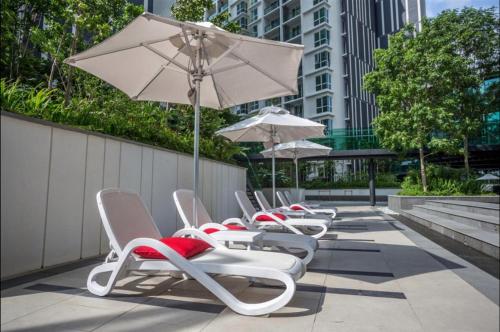 a row of lounge chairs and an umbrella at The Shore Hotel & Residences By Lá VISTA in Melaka