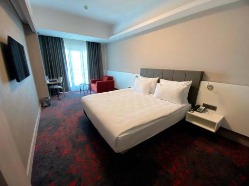 ein Hotelzimmer mit einem großen Bett und einem Stuhl in der Unterkunft SPARK HOTEL RESIDENCE KONYA in Yazır