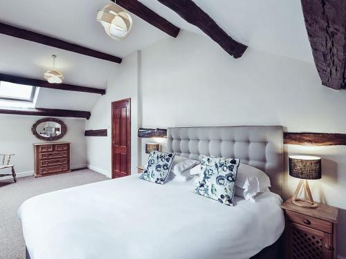 a bedroom with a large white bed with blue pillows at Stable End Cottage in Bouth