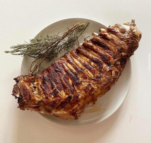 a piece of meat on a white plate with rosemary at B&B Villa Flora in Santeramo in Colle