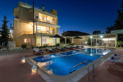 a swimming pool in front of a house at night at Kallithea Breeze Luxury Villa in Koskinou