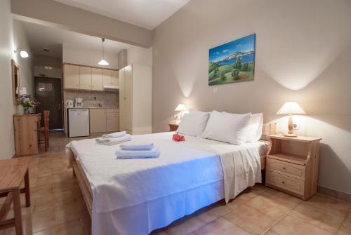 a bedroom with a large white bed and a kitchen at Spiti Marias by Thanos Village in Gialova