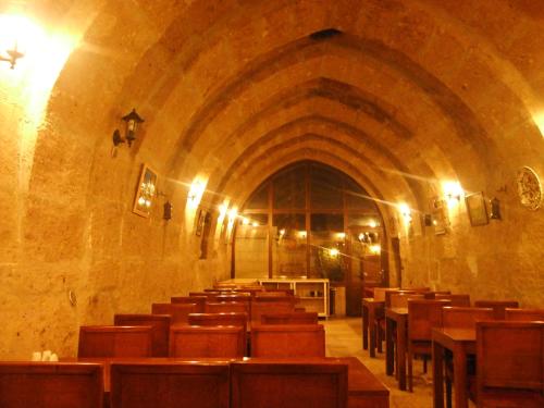 an empty church with wooden tables and chairs at Kapadokya Ihlara Konakları Otel Konak Odaları in Guzelyurt