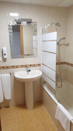 een badkamer met een wastafel, een douche en een spiegel bij Platea de Sevilla in Sevilla