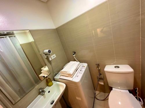 a bathroom with a toilet and a sink and a mirror at Luxury Seaside Sunset view at the Shore Mall of Asia in Manila