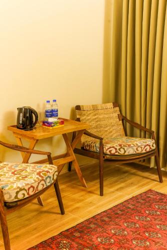 a living room with a table and two chairs and a table and a table at Walnut Heights By Roomy, Kalam in Kalām