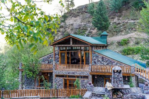 a stone house with a green roof at Walnut Heights By Roomy, Kalam in Kalām