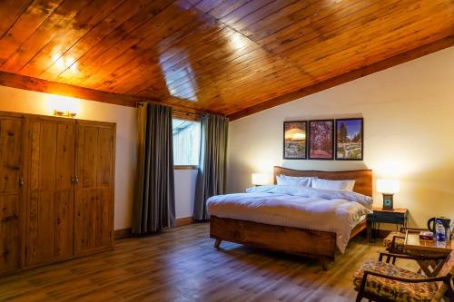 a bedroom with a bed and a wooden ceiling at Walnut Heights By Roomy, Kalam in Kalām